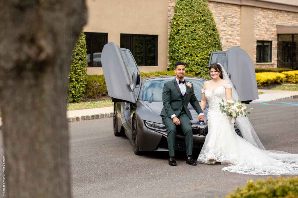 bride and grrom posing with a sports car
