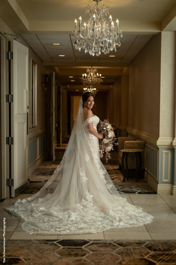 the bride posed in the hallway showing off her long veil and train.